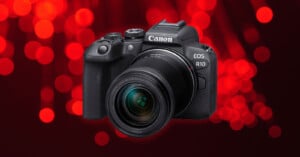 A Canon EOS R10 camera with a lens is shown against a background of red circular bokeh lights.