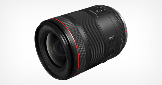 A black camera lens with a red ring near the front. It has textured grip sections, and switches labeled “AF/MF” and “IS”. The front reads "20" and other markings. The lens is angled slightly to the left.