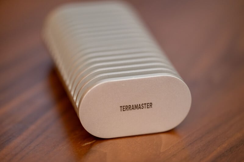 A close-up photo of a silver, ribbed electronic device with the brand name "TERRAMASTER" printed on one end, placed on a wooden surface.