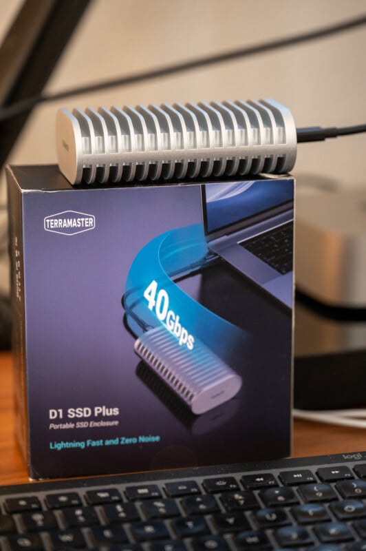 A TerraMaster D1 SSD Plus portable SSD enclosure rests on its box, which highlights "40Gbps" and "Lightning Fast and Zero Noise." A keyboard and part of a laptop are visible in the background.