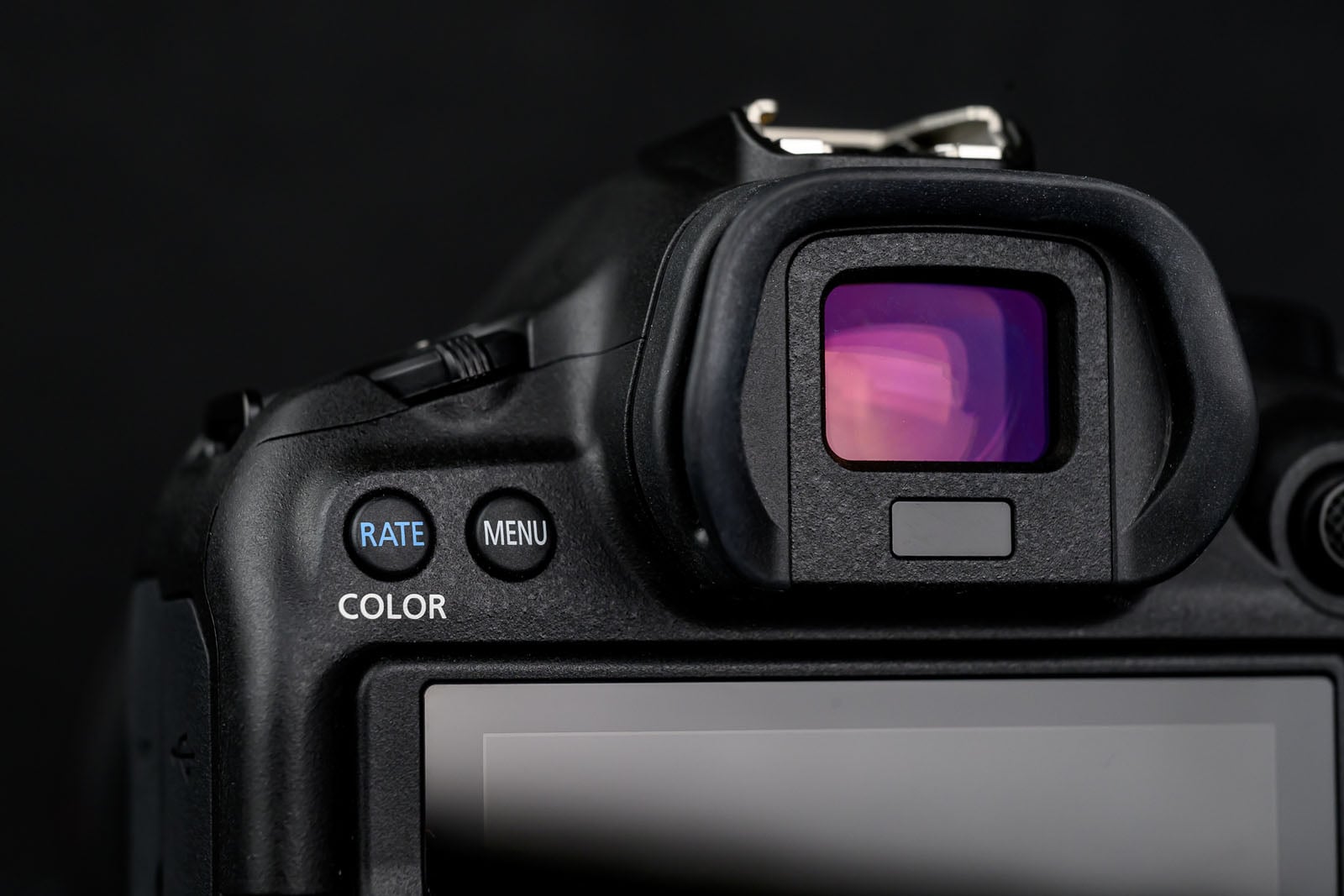 Close-up view of a digital camera's rear, focusing on the electronic viewfinder, RATE and MENU buttons, and part of the LCD screen, against a black background.