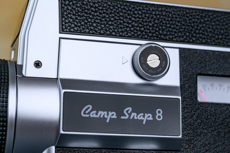 Close-up of a vintage camera labeled "Camp Snap 8," showing a textured black and silver body with a visible dial and part of a gauge.