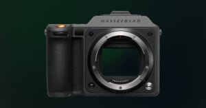 Front view of a Hasselblad medium format camera body without a lens, showing the sensor, textured grip, and brand name on a dark green gradient background.