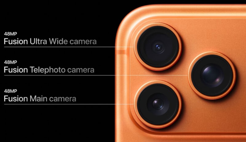 Close-up of an orange smartphone’s triple camera system, labeled as 48MP Fusion Ultra Wide, 48MP Fusion Telephoto, and 48MP Fusion Main camera, on a black background.