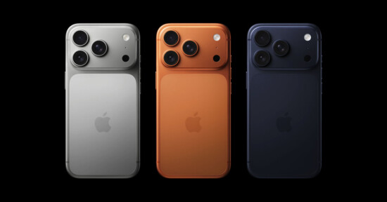 Three iPhones are shown from the back in silver, orange, and dark blue colors, each with three camera lenses and the Apple logo, on a black background.