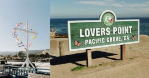 A green and white sign reading "Lovers Point, Pacific Grove, CA" stands near the ocean; next to it is a nautical mast with colorful signal flags at a seaside pier under a clear blue sky.