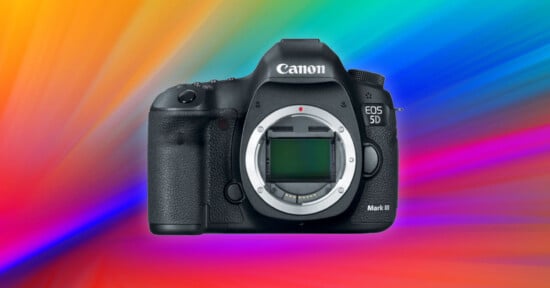 A Canon EOS 5D Mark IV camera body is displayed against a vibrant, multicolored background with swirling blue, pink, and orange hues. The camera sensor and control buttons are clearly visible.
