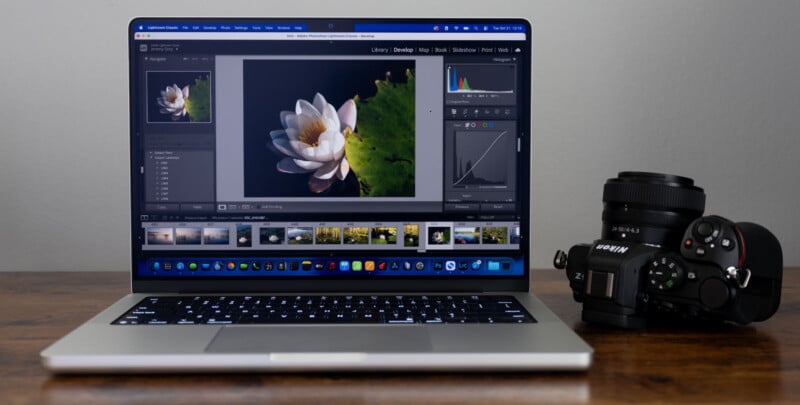 A laptop displaying photo editing software with a water lily image on the screen sits on a wooden desk next to a black Sony digital camera with a lens attached.
