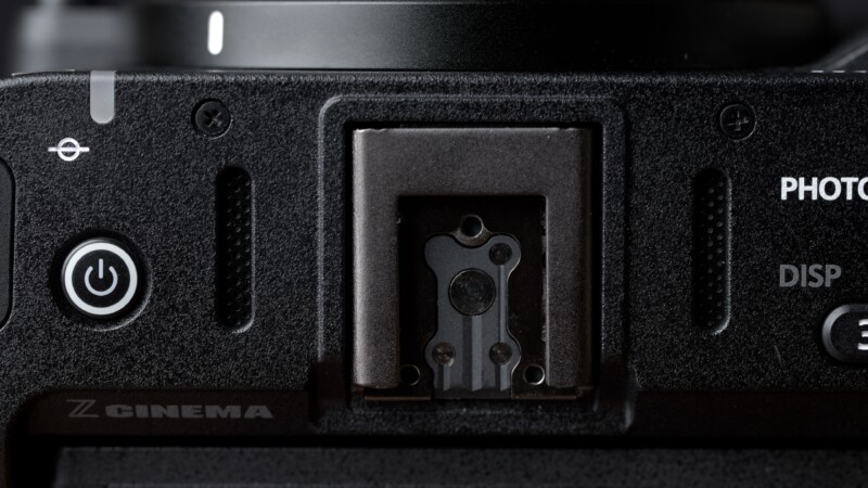 Close-up view of a camera's hot shoe mount, power button, and part of the display controls, with the "Z CINEMA" label partially visible in the lower left corner.