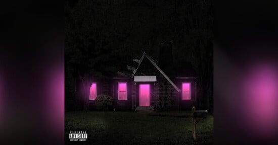 A dark house surrounded by trees at night, with glowing pink light shining from the windows and door. A mailbox and a parental advisory label are visible in the front yard.