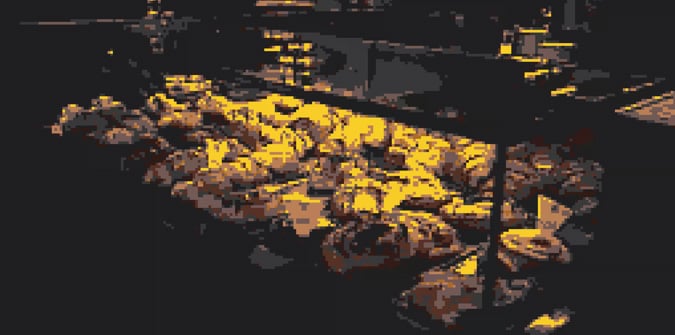 A display case filled with various pastries and baked goods, illuminated by warm yellow lighting in an indoor setting.