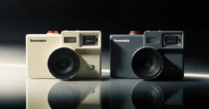 Two retro-style cameras, one beige and one black, labeled "Rewindpix," are side by side on a glossy surface with a dark background. Both cameras feature large lenses and prominent viewfinders.
