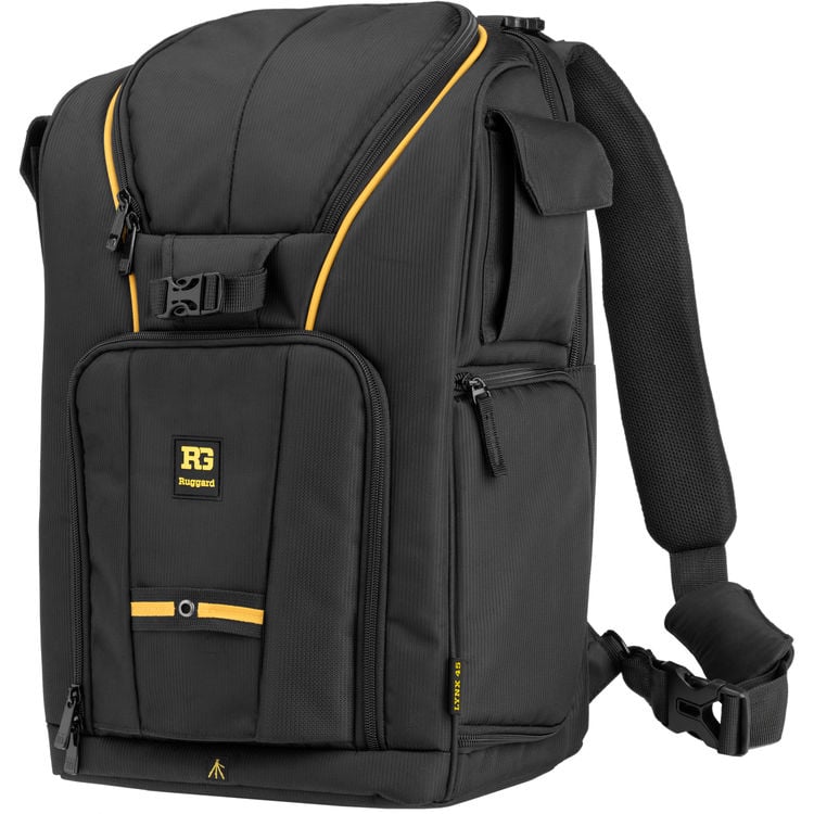 A black Rugged backpack with yellow accents, padded shoulder straps, multiple zippered compartments, and a front flap featuring the RG Rugged logo.