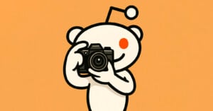 Illustration of Reddit’s alien mascot, Snoo, holding and pointing a camera toward the viewer, set against an orange background.