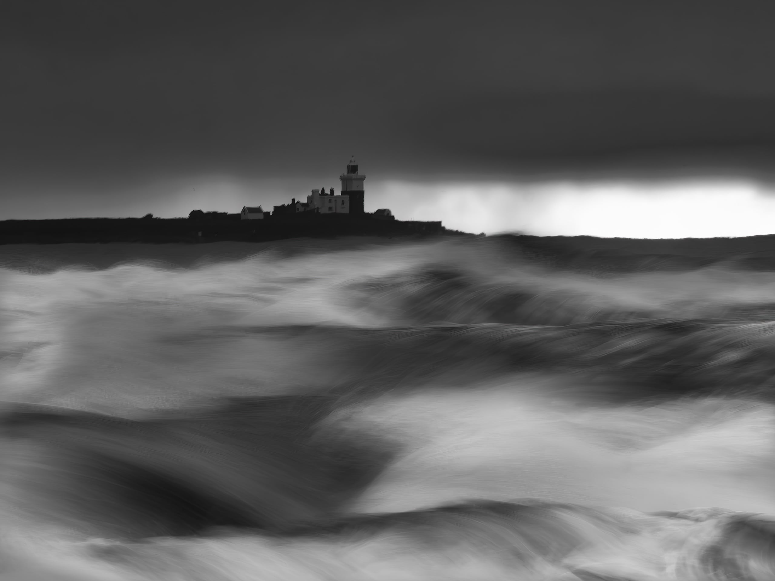 A black and white photo of a lighthouse and buildings on a distant shore, silhouetted against a dramatic sky, with large, blurred waves crashing in the foreground.