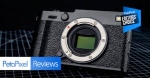 A black digital camera body without a lens is displayed on a grid-patterned surface. The image includes "PetaPixel Reviews" and an "Editors' Choice" badge in the corners.
