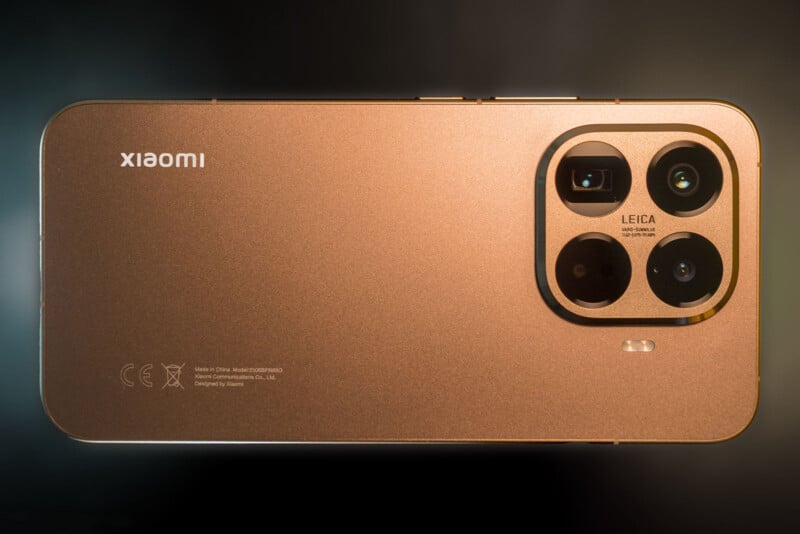 A close-up of the back of a gold Xiaomi smartphone, showing the Xiaomi logo and a triple Leica camera setup with an LED flash on the top right corner.