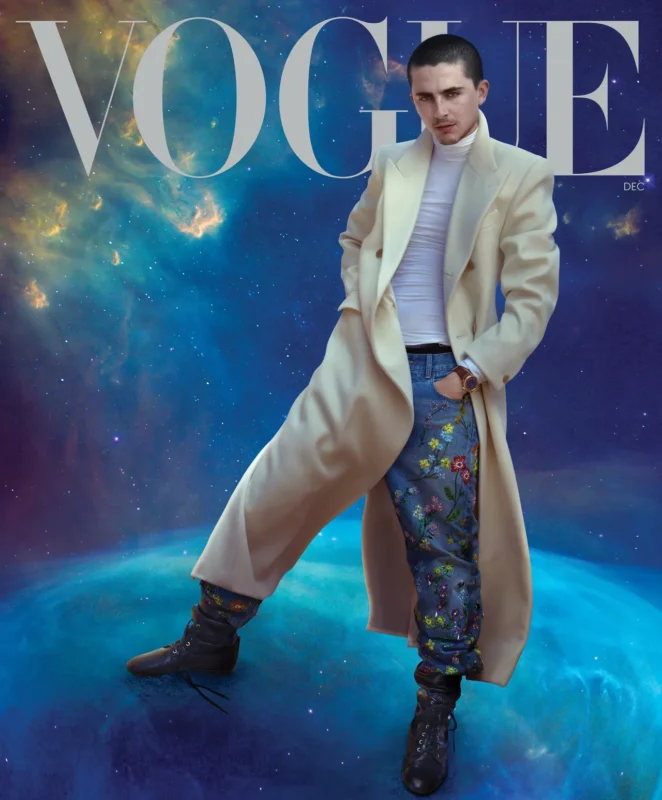 A person in a long cream coat, white turtleneck, and floral embroidered pants poses confidently on the cover of Vogue, set against a galaxy-inspired background.